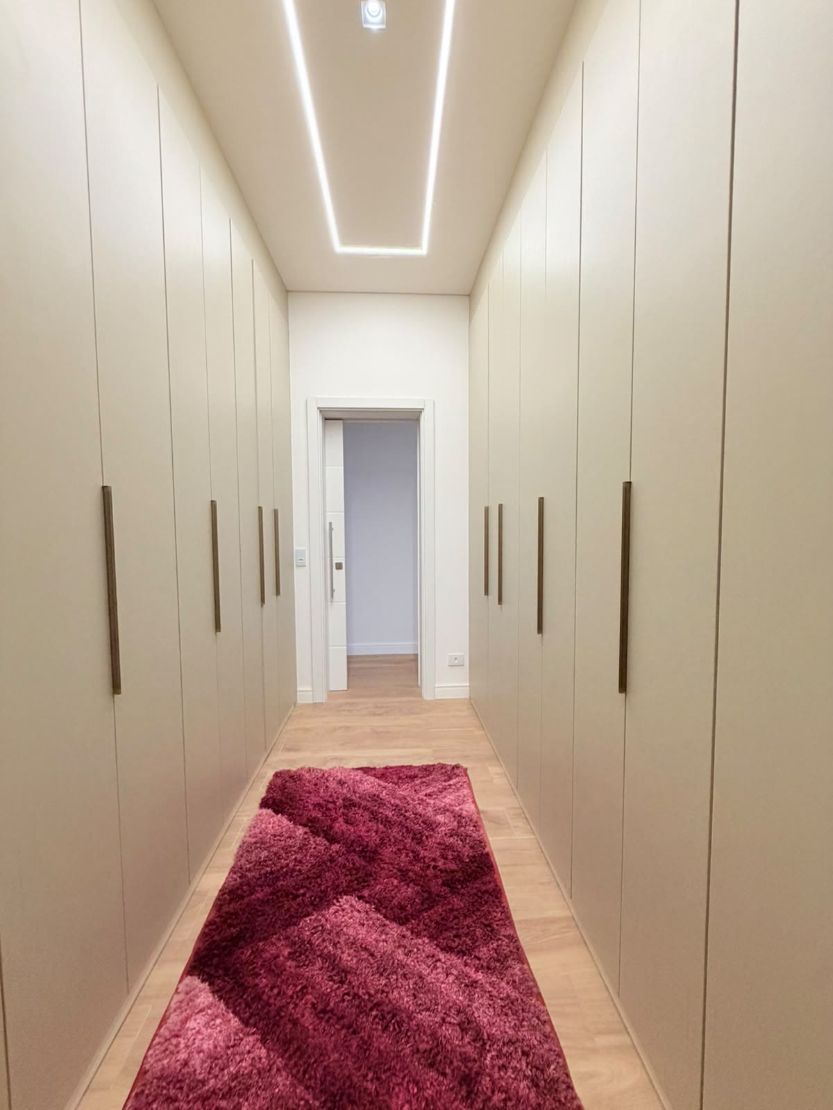 Closet com armários do piso ao teto e iluminação linear