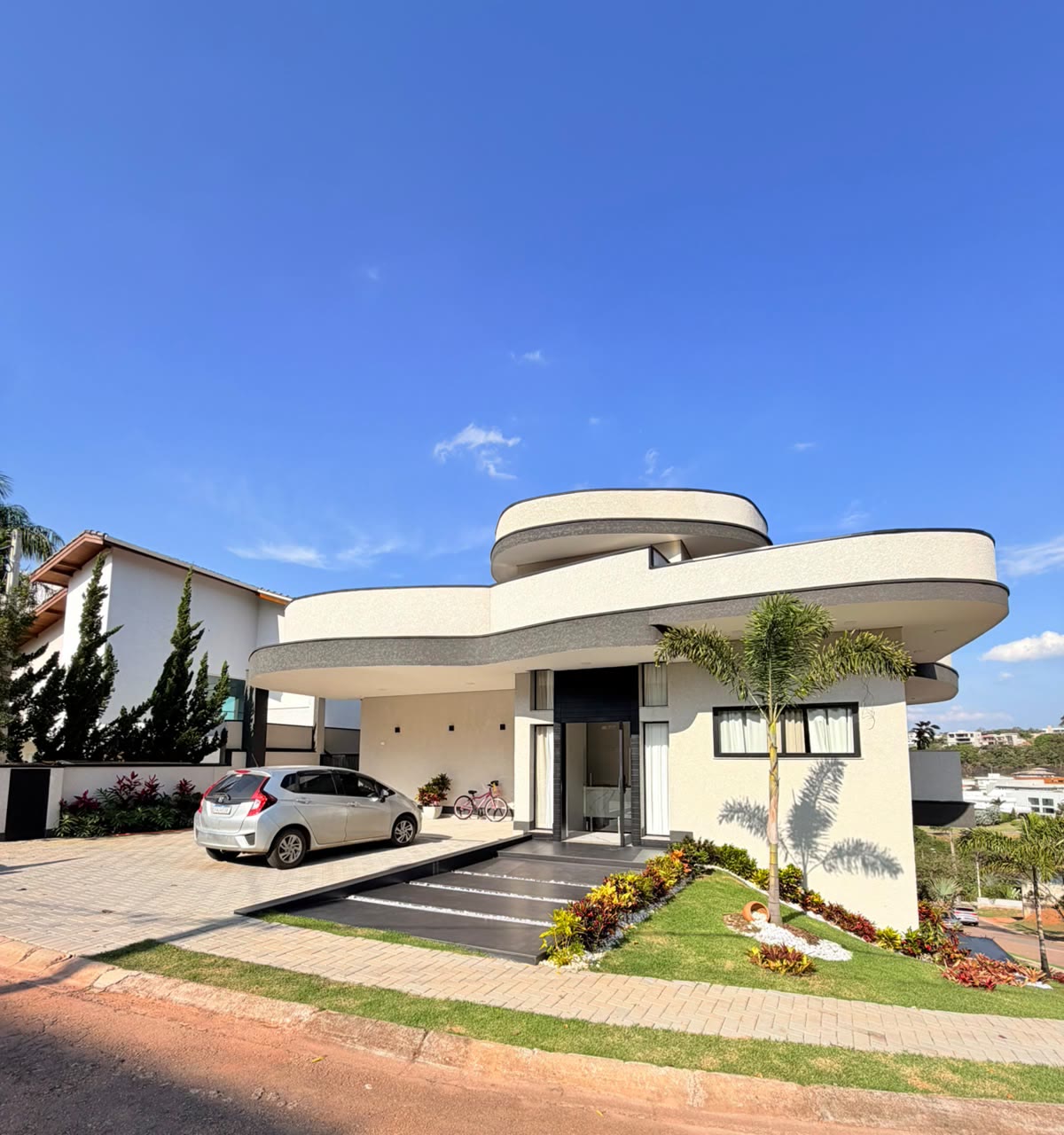 Fachada principal com volumes curvos e jardim frontal