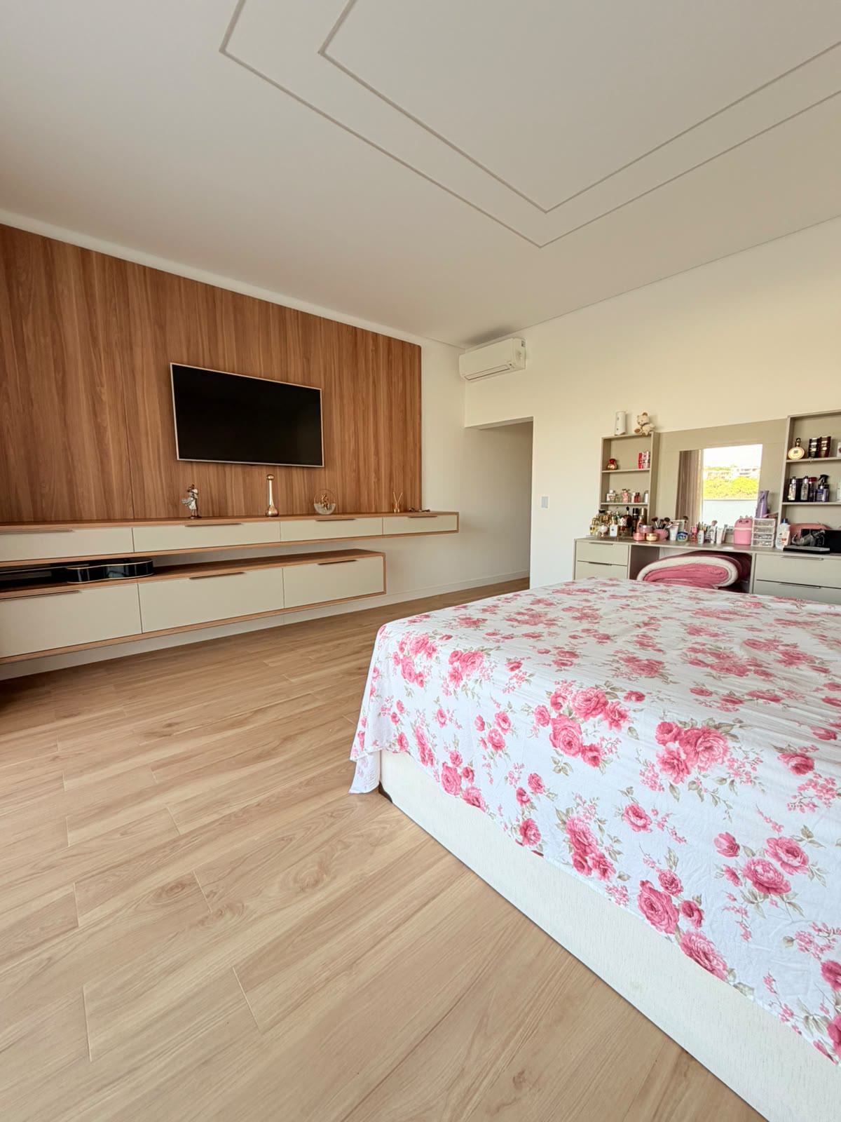 Suíte principal com painel de TV em madeira